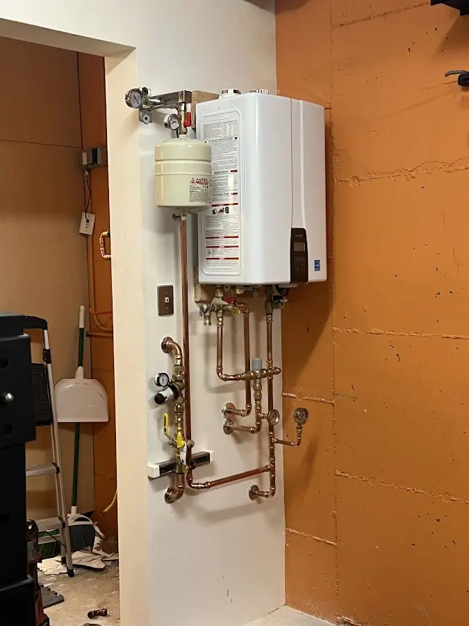 Plumbing technician inspecting water heater connections in Marquette